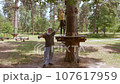A child in a forest adventure park made of ropes. 107617959