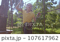 A child in a forest adventure park made of ropes. 107617962