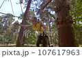 A child in a forest adventure park made of ropes. 107617963