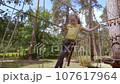 A child in a forest adventure park made of ropes. 107617964