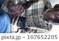 vertical video a young brunette near the window writes a message on a smartphone searches for information on the Internet. close-up 107652205