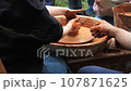 Pottery training. Making a clay pot on a potter's wheel. Manufacturing process. 107871625