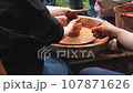 Pottery training. Making a clay pot on a potter's wheel. Manufacturing process. 107871626