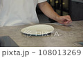 A man puts a white plate and a wine glass on the table 108013269