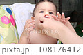 a small child sits on a baby feeding chair and eats a peach in the summer. Childhood concept. Close-up shot 108176412