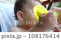 Portrait of a little boy who sits on a child's chair. Happy child drinks milk, kefir or dairy products from a cup. Correct and natural nutrition for children 108176414