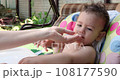 a small child sits on a baby feeding chair and eats a peach in the summer. Childhood concept. Close-up shot 108177590