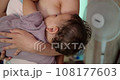 a small child sleeps peacefully on the mother's chest. mom shakes the baby in her arms 108177603