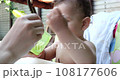 Portrait of a little boy who sits on a child's chair. Happy child drinks milk, kefir or dairy products from a cup. Correct and natural nutrition for children 108177606