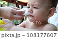 Mother cleans and wipes baby's mouth after eating with baby wipe 108177607