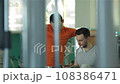 A young man smiling and discussing with his fitness trainer the sports magazine 108386471