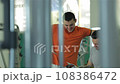 A young man smiling and discussing with his fitness trainer the sports magazine 108386472