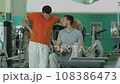 A young man with his fitness trainer 108386473