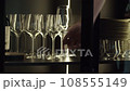 Hand opens cabinet door to reveal several crystal goblets. Concept of restaurant or celebration. 108555149