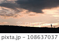 A boy running along the river bank under the sunset sky 108637037