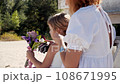 Mom and daughter in white dresses spend time together on the beach and have fun 108671995