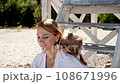 Mom and daughter in white dresses spend time together on the beach and have fun 108671996