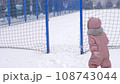 5 years old girl enjoying winter day on a fenced sports ground. Fun winter holidays. Playing with snow in a beautiful snowfall. Holiday outdoors in cold winter 108743044