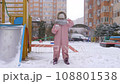 5 years old girl enjoying winter day on a fenced sports ground. She approaches the camera with a snowball in her hand wrapped in a warm scarf. Fun winter holidays. Holiday outdoors in cold winter 108801538