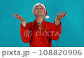 Happy woman in festive mood. Gold tinsel is falling down to the woman's palm.  108820906