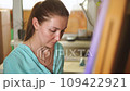 A adult female brunette artist paints a painting on canvas in her creative studio 109422921