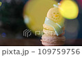 Snowman dessert macaron decorated with hat and scarf with colorful lights and flashing bokeh on foreground and Christmas tree on background. Merry Christmas and Happy New Year festive concept 109759756