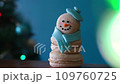 Snowman dessert macaron decorated with hat and scarf against Christmas tree, colorful lights and bokeh background. Camera moves towards the object. Merry Christmas and Happy New Year festive concept 109760725