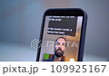 A young man shoots a video on a smartphone while reading text from a teleprompter on a screen 109925167