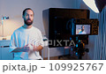 A young male blogger records a video with teleprompter for his YouTube channel in his studio. 109925767