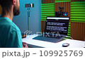 A young man shoots a video on a camera while reading text from a teleprompter on a laptop 109925769