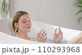 Relaxed beautiful woman taking salt bath at home. Side view of pretty blonde female with closed eyes soaking in modern bathtub at luxury resort, in slow motion. Concept of self care, recreation, spa.  110293968