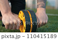 Handsome athletic man doing abs exercises using abdominal roller at stadium 110415189