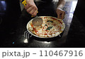 A man cuts a pizza into triangular pieces 110467916