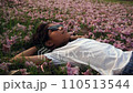Asian kids with sun glasses on summer brunette girl lays down in flower meadow and smelling the flowers thoughtfully romantic slow shot 110513544