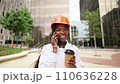 Happy black woman in helmet standing with coffee cup in daylight 110636228