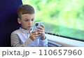 Pre teen boy traveling by train and using smartphone. Boy entertaining with net surfing viral videos or play games. 110657960