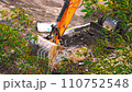 Excavator transferring a ground with a heavy bucket. Excavator at work. Tractor with a bucket on a construction site. A construction machine is making a road. Excavator bucket breaks the road asphalt 110752548