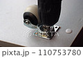 The screwdriver tightens the screw. An electric handheld screwdriver drives a black hardened screw into a wooden slab and secures a furniture wheel. Furniture assembly workshop. Close-up of screw 110753780