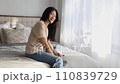 Attractive smiling asian woman in casual clothes sitting on the bed at home 110839729