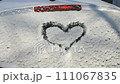 Heart drawn in snow on the rear window of a car. Close-up 111067835