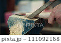 Video. Carpenter sharpens wooden product with file on workbench and sawdust flies. Close-up. Hands 111092168