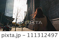 Rear view of female tourist walking along the iconic Manhattan Bridge in bright sunlight. 111312497