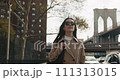 Free and happy attractive female enjoying walking in New York streets with the iconic Brooklyn Bridge in the back 111313015