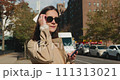Portrait of stylish attractive female wearing glasses and admiring New York streets, while using smartphone 111313021