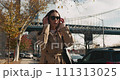Medium shot of attractive brunette female putting on the sun glasses and walking in front of the famous Manhattan Bridge 111313025