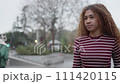 Urban Wanderlust: Confident Young Woman with Afro Hair Strolling through City Streets 111420115