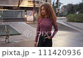 Circular motion around a young woman with curly hair. They stand with a white and maroon striped sweater 111420936