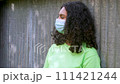 Beautiful mixed race African American girl biracial teenager young woman outside wearing a face mask in an urban city environment during COVID-19 Coronavirus pandemic 111421244