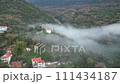 Aerial view: Foggy valley with houses, trees, and natural landscape 111434187