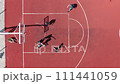 Aerial top down view of teenagers playing basketball on a public outdoor court. Young men throwing a ball into a basketball basket at their college playground. 111441059